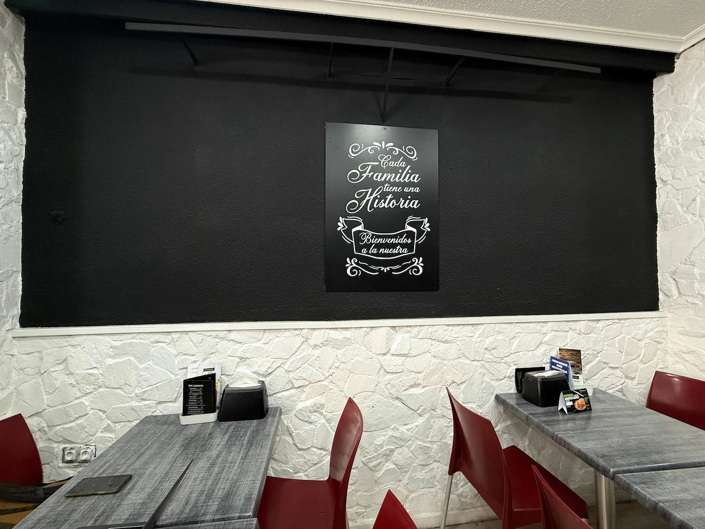 Algunas de las mesas del Café-Bar Caminito, con una de las frases más repetidas tras su mostrador de fondo.