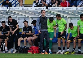 José Luis Acciari se lamenta de un lance dentro del terreno de juego en el último partido de Unionistas, mientras su staff consulta datos.