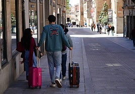 Varios salmantinos con maletas en una calle céntrica de la ciudad.