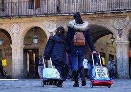 Una madre pasea con su hija por la Plaza Mayor con una mochila.