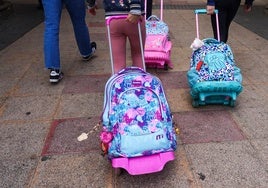 Varias niñas salen de su centro escolar con sus mochilas.