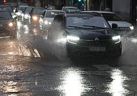 Varios vehículos circulan como pueden bajo la intensa lluvia caída en Valladolid este martes.