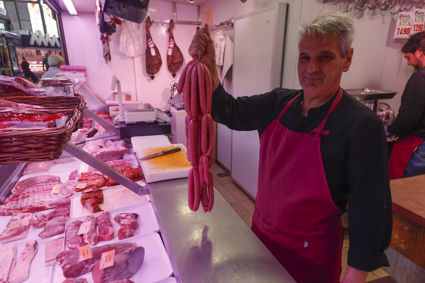 Uno de los carniceros del Mercado, cogiendo unas salchichas.