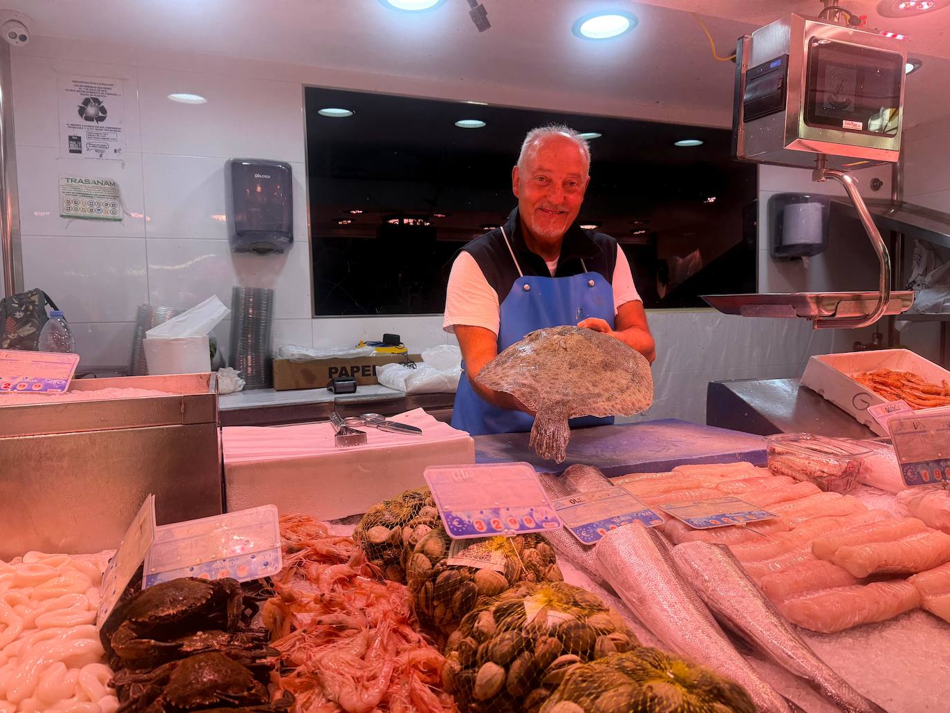 Uno de los pescaderos del Mercado sujeta un gallo.
