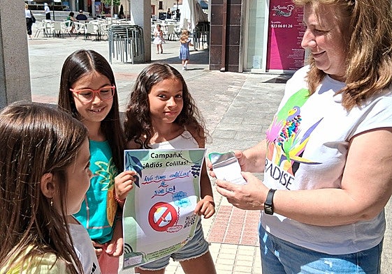 Los niños informando a una vecina de la campaña 'Adiós colillas'.
