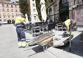 Trabajadores arreglan una acera en una calle del centro de Salamanca.