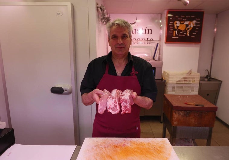Agustín, carnicero del Mercado Central, sujeta tres plumas tras el mostrador de su estand.