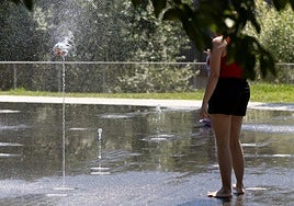 Una joven se refresca en una fuente.
