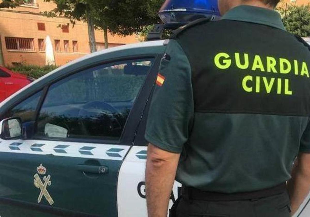 Imagen de un agente frente a un coche de la Guardia Civil.