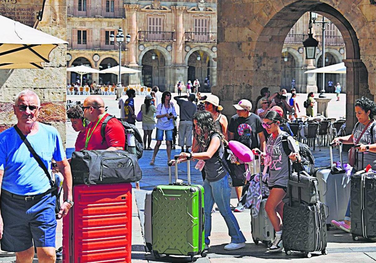Un grupo de viajeros con grandes maletas por la plaza del Corrillo.