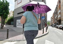Una mujer pasea mientras se resguarda del sol.