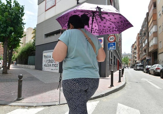 Una mujer pasea mientras se resguarda del sol.