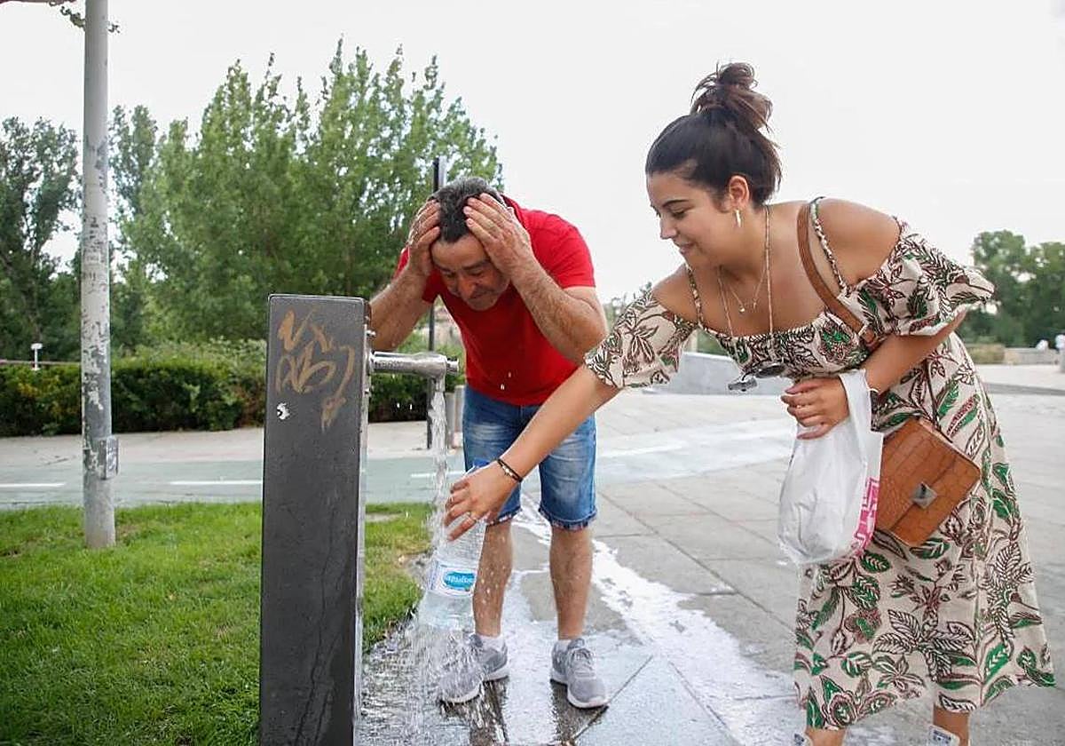 Dos salmantinos se refrescan en una fuente.