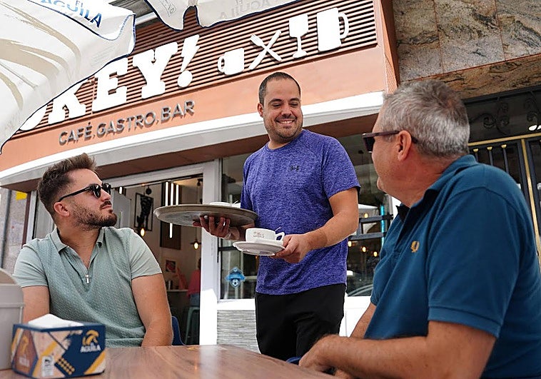 Alberto Elvira, sirviendo unos cafés a unos clientes habituales en la terraza del bar Okey.