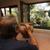Gerardo, trabajando en una pieza en su taller mientras Reyes riega las plantas del jardín.