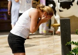 Una mujer se refresca en una fuente.