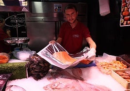Un pescadero del Mercado Central sostiene un pedazo de salmón.