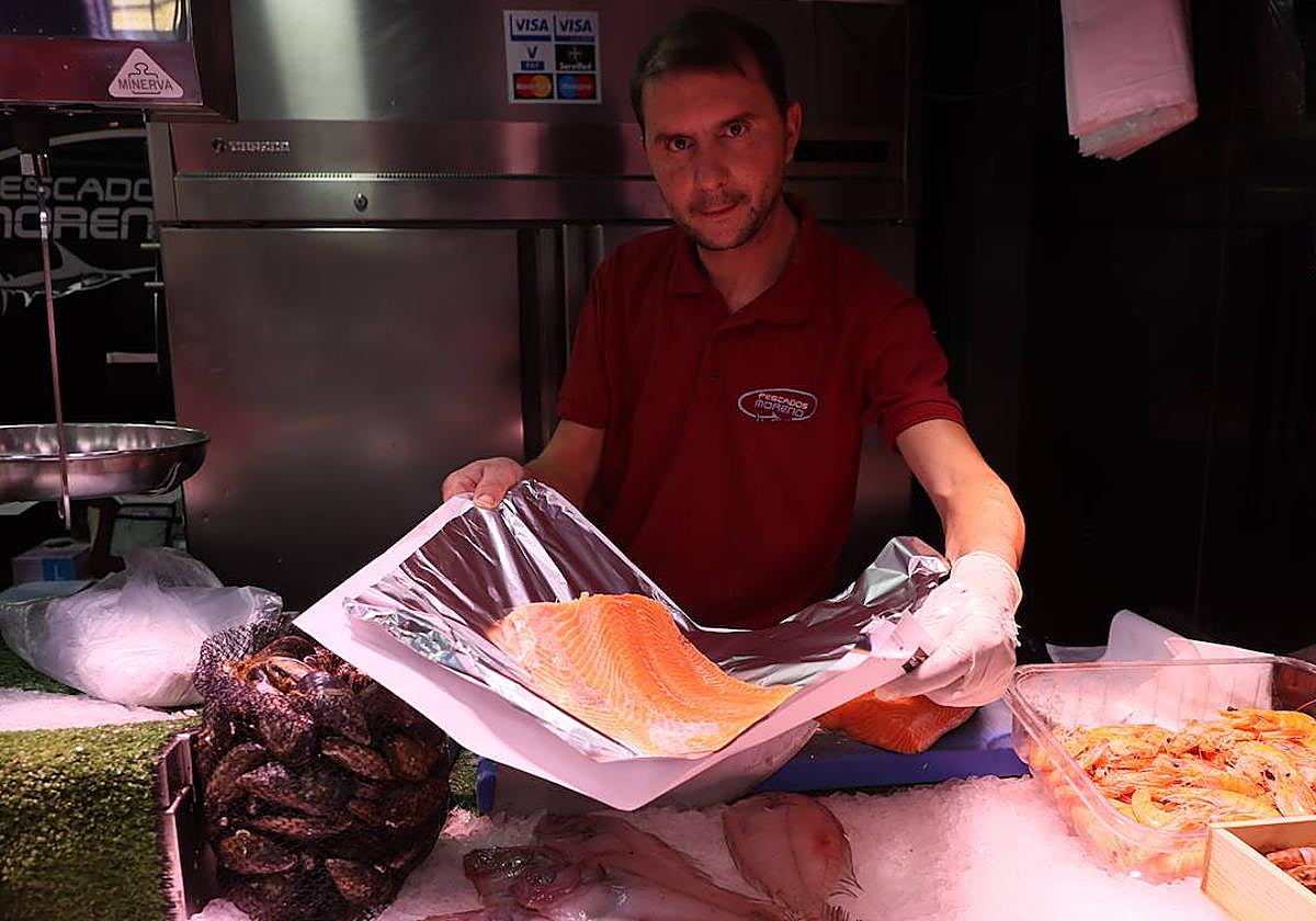 Un pescadero del Mercado Central sostiene un pedazo de salmón.