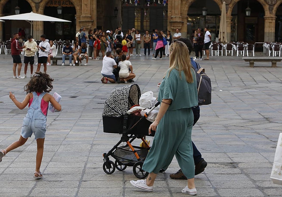 Una pareja con un carrito de bebé por la Plaza Mayor.