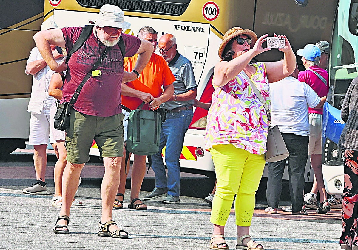 Viajeros extranjeros junto a las dársenas para autobuses turísticos en la plaza del Mercado Viejo.