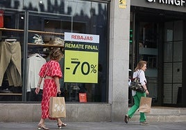 Varias salmantinas pasean frente a un escaparate de la ciudad.