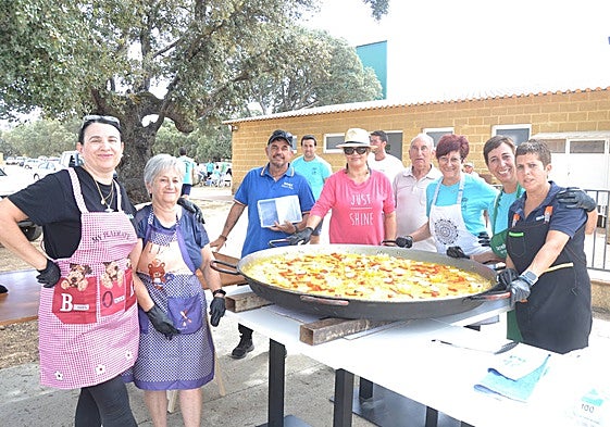 Las voluntarias y voluntarios posan junto a una de las dos paelleras