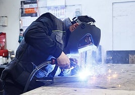 Un trabajador de un taller soldando piezas.