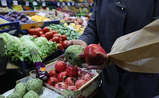 Nati, frutera del Mercado, sostiene una chirimoya y una granada.