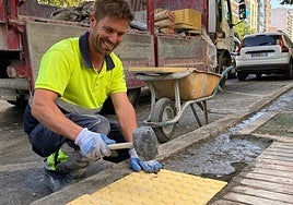 Un operario coloca las baldosas podotáctiles que avisan del límite de la parada de autobús.