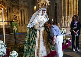 Una mujer rinde honores a la virgen participando en el besamanos.