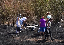 Vecinos, refrescando una zona afectada por un incendio este verano.