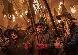 Varias personas caminan con antorchas en la celebración de la Procesión Cívica del Vítor.