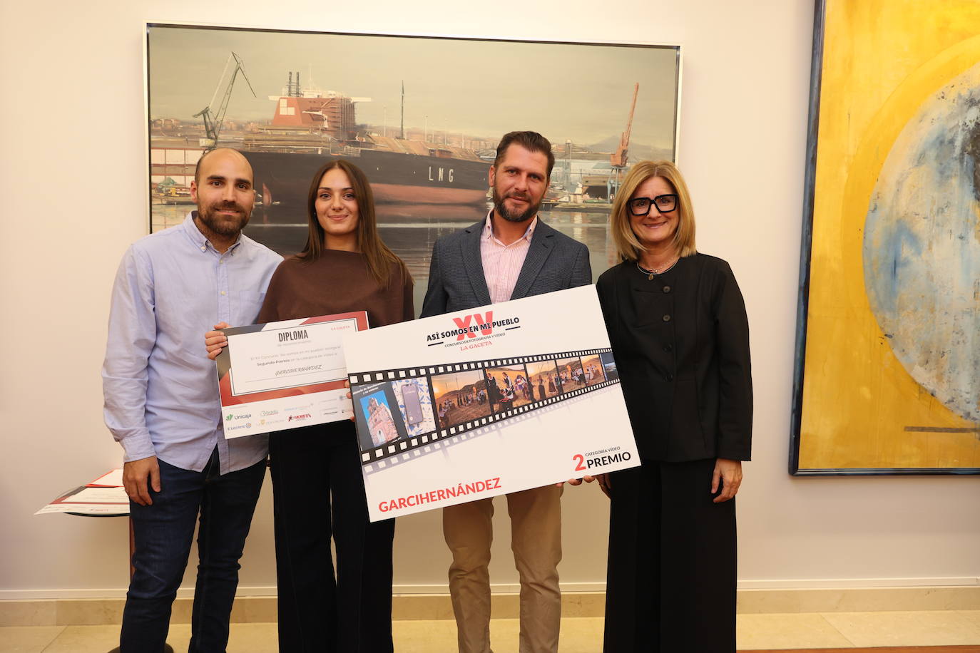 Alberto Fuentes, gerente de la empresa Proyecfilm y María José Rivera, de Unicaja, entregan el segundo premio al vídeo de Garcihernández. Reciben el galardón Manuel Jesús Sánchez, alcalde de la localidad, y Andrea Sánchez, la vecina que se encargó de organizar tanto el posado como el vídeo. El pueblo disfrutará de una proyección de cine al aire libre.