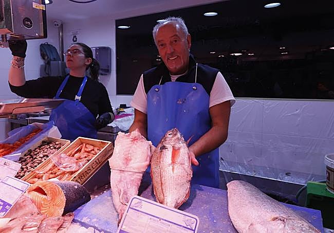 Un pescadero sostiene un rape y un besugo.