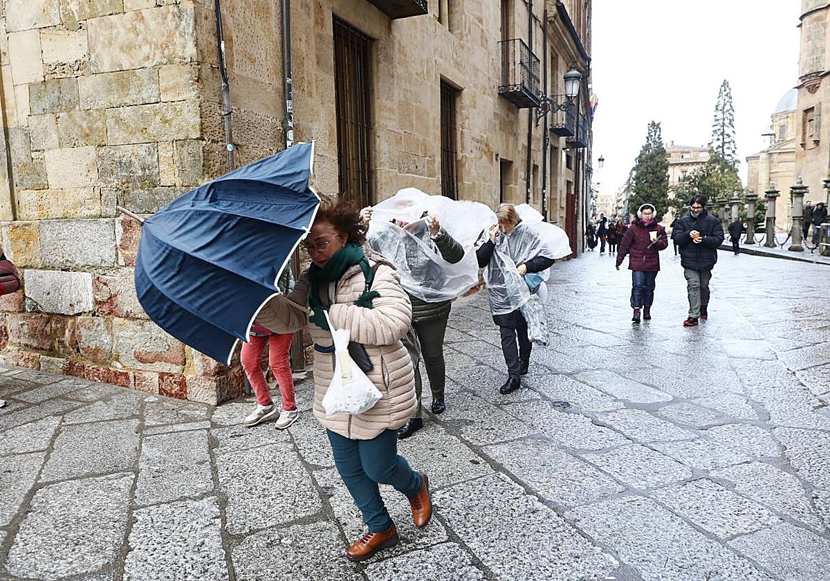 Varias personas 'luchan' contra el aire y el mal tiempo en Salamanca.