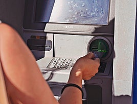 Una mujer saca dinero de un cajero automático.