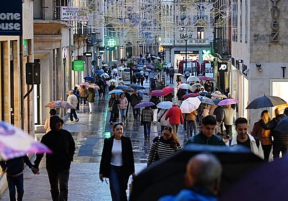 Salmantinos se refugian de la lluvia con paraguas en la tarde de este jueves.