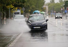 Un coche atraviesa la carretera llena de agua.