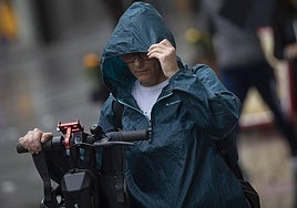 Una mujer se coloca la capucha para protegerse de la lluvia.