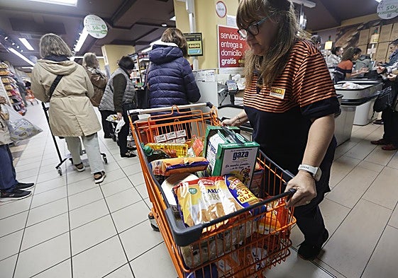 Una trabajadora de una gran superficie recoge algunas donaciones de alimentos en un carrito de la compra.