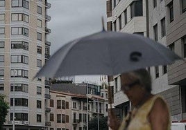 Una mujer se protege de la lluvia con un paraguas.