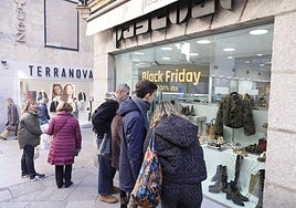 Varias personas, frente al escaparate de un establecimiento con descuentos por el Black Friday.