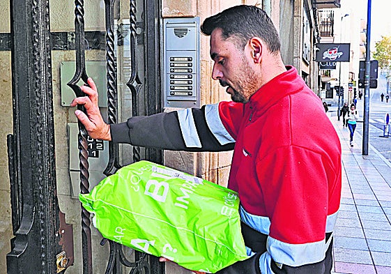 Un repartidor entra en el portal de un edificio de Salamanca para entregar un paquete.