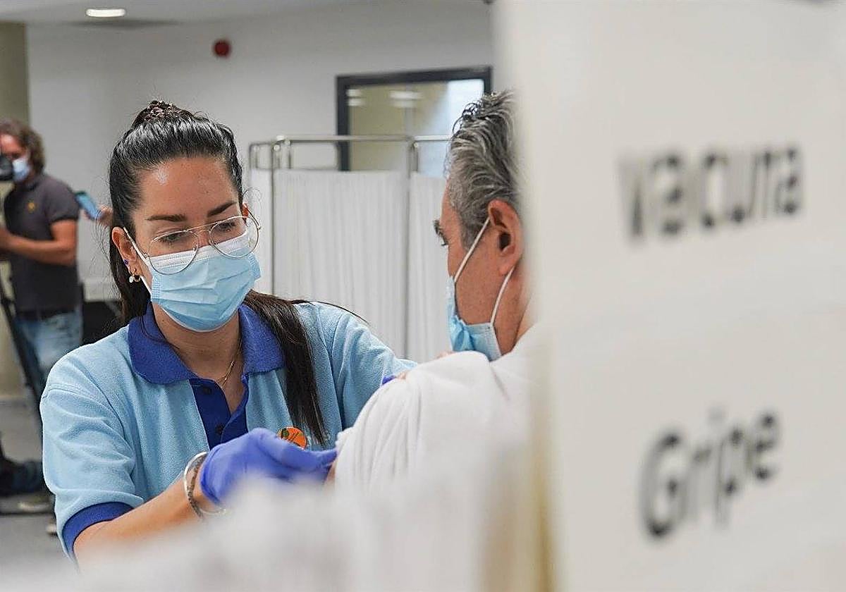 Una enfermera, vacunando a una persona de la gripe.