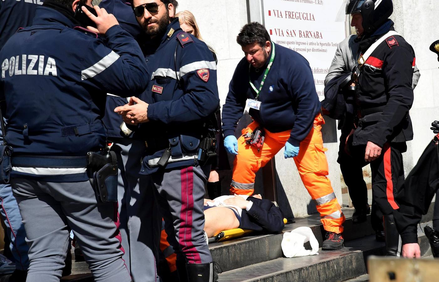 Policías y miembros de los servicios de rescate asisten a un herido a las puertas del Palacio de Justicia en Milán.