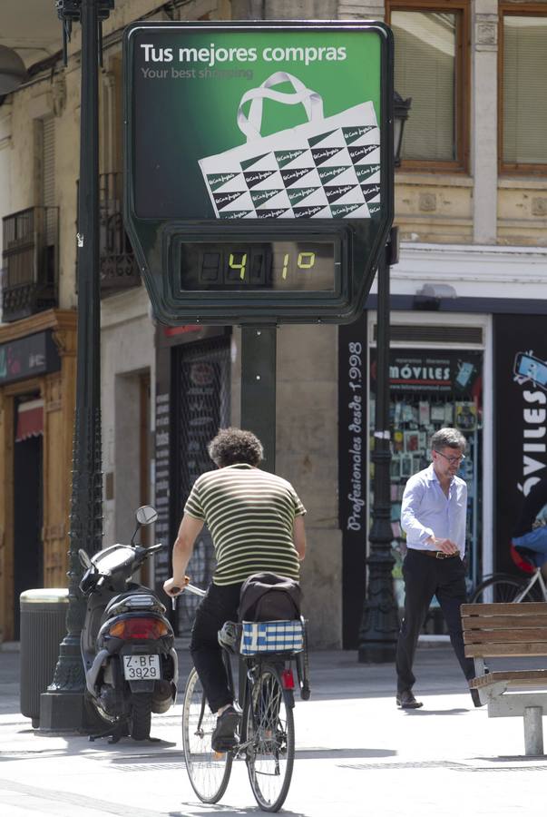 Dos personas pasan por delante de un termómetro en Zaragoza.