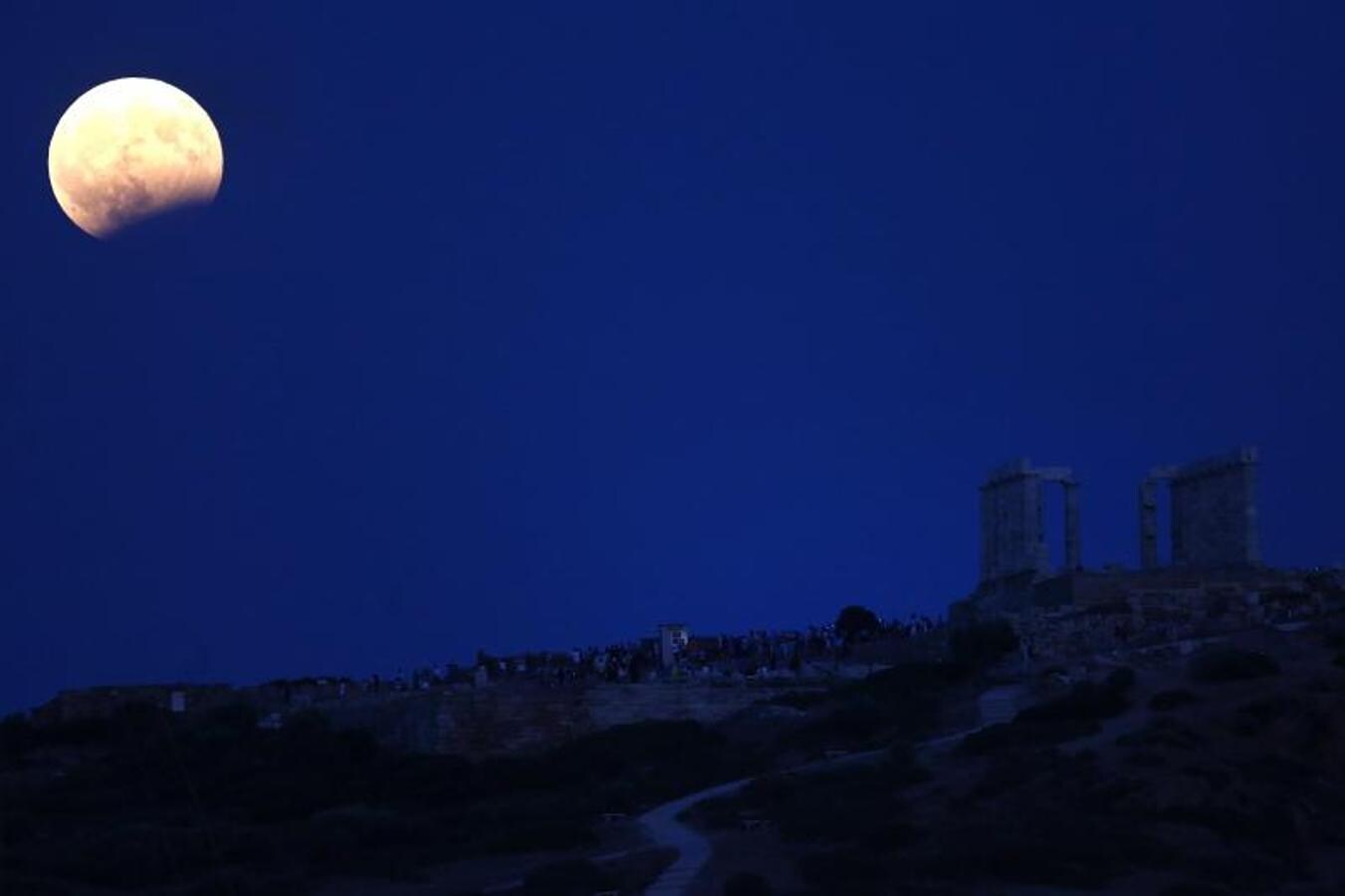 Vista de la luna llena sobre el templo de Poseidón, en Atenas, antes del pico del eclipse lunar parcial.