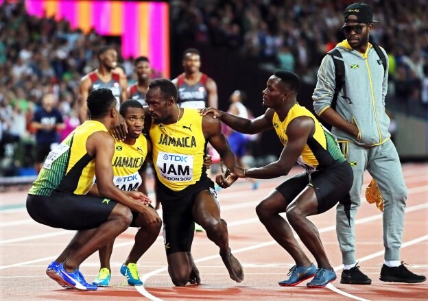 Los compañeros de Bolt le ayudan a levantarse tras la lesión. :: efe