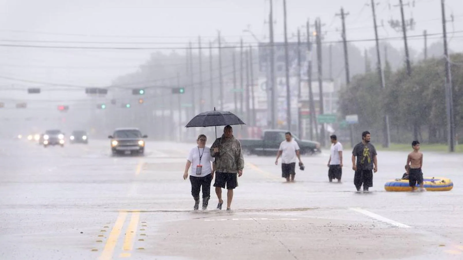Los residentes caminan por la inundada carretera Texas 249 cuando evacuan sus barrios adyacentes.