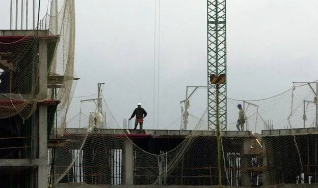 Dos obreros trabajan en las obras de construcción de un edificio de viviendas. 